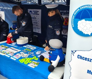 Policjanci w namiocie okazują dzieciom gadżety.
