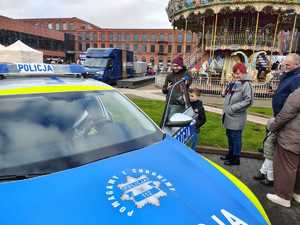 Radiowóz policyjny dookoła ludzie.