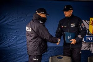 Komendant z przedstawicielem z KGP stoja pod namiotem podają sobie ręce.