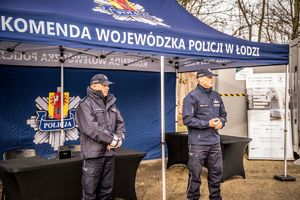 Komendant z przedstawicielem z KGP stoja przy namiocie.