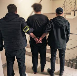 Policjanci stoją z zatrzymanym mężczyzną.