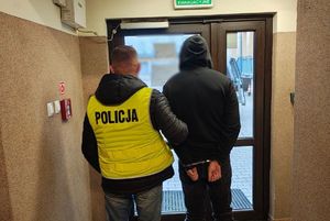 Policjant stoi z zatrzymanym mężczyzną.