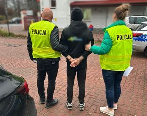 Policjanci stoją z zatrzymanym mężczyzną.