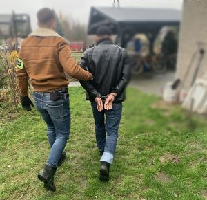 Policjant idzie z zatrzymanym mężczyzną.