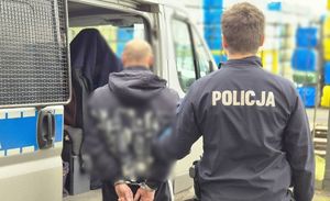Policjant stoi z zatrzymanym mężczyzną.