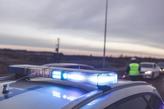 Kogut na radiowozie policyjnym w tle autostrada.