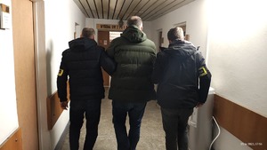 Funkcjonariusze prowadzą zatrzymanego.