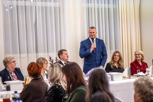 Zaproszeni goście przy wspólnym stole. Komendant mówi przez mikrofon.