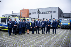 Policjanci na tle radiowozów.