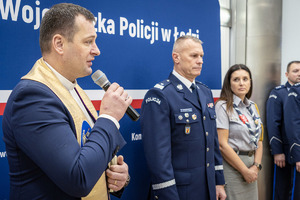 Przemawia ksiądz obok policjant w mundurze i harcerka.