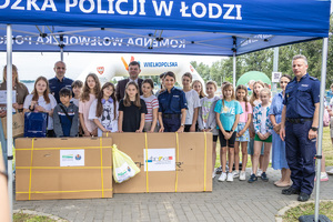 Komendant  na pikniku wraz z dziećmi stoją pod namiotem.