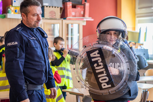 Policjant obok dziecko z tarcza i hełmem.