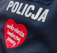 Napis policja na granatowym tle i serduszko WOŚP.