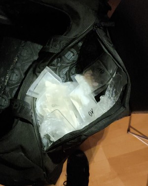 Biały proszek w torbach foliowych w czarnej torbie.