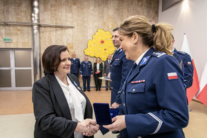 Komendant przypina medal i gratuluje pracownikowi cywilnemu.