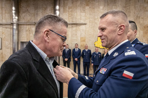 Komendant przypina medal i gratuluje pracownikowi cywilnemu.