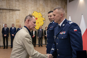 Komendant przypina medal i gratuluje pracownikowi cywilnemu.