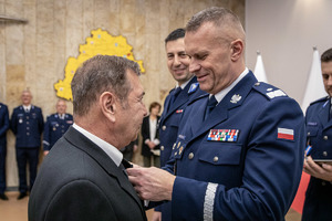 Komendant przypina medal i gratuluje pracownikowi cywilnemu.