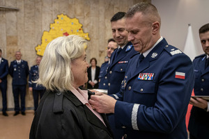 Komendant przypina medal i gratuluje pracownikowi cywilnemu.