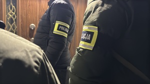 Policjanci stoją przed drzwiami.