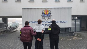 Policjanci z zatrzymanym na tle komendy.