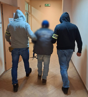 Policjanci prowadzą zatrzymanego.