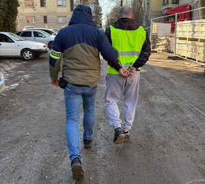 Policjant prowadzi zatrzymanego.