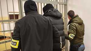 Policjant z zatrzymanym przy kratach.