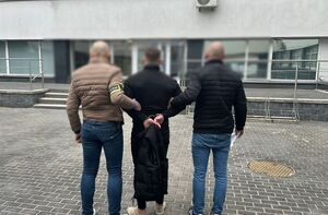 Policjanci stoją z zatrzymanym mężczyzną.