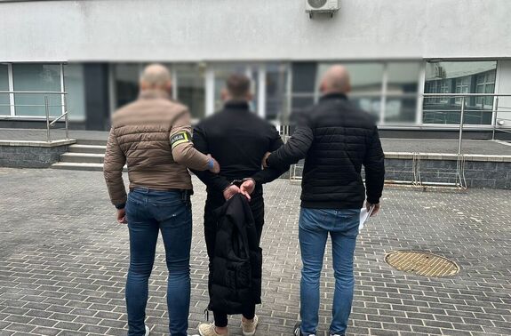 Policjanci stoją z zatrzymanym mężczyzną.