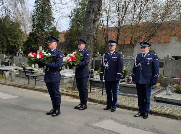 Policjanci z wieńcami na cmentarzu.