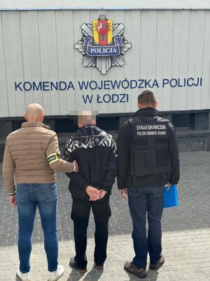 Policjant i strażnik graniczny stoją z zatrzymanym mężczyzną.