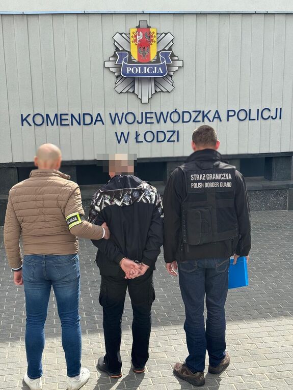 Policjant i strażnik graniczny stoją z zatrzymanym mężczyzną.