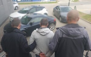 Policjanci prowadzą zatrzymanego mężczyznę.