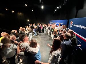 Uczestnicy wydarzenia stoją w okręgu i obejmują się.