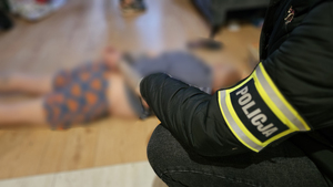 Policjant kuca przy zatrzymanym mężczyźnie.