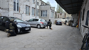 Policjanci klęczą przy samochodach.
