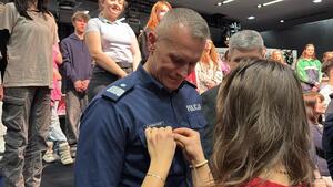 Uczestnicy wydarzenia stojący na scenie, przed sceną goście, podczas wręczenia odznaczenia.