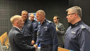 Zaproszeni goście ściskają sobie dłoń przed sceną.