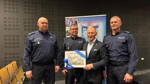 Zaproszeni goście na tle baneru wydarzenia z obrazem w ręku.