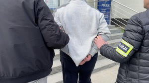 Policjant prowadzi zatrzymanego.