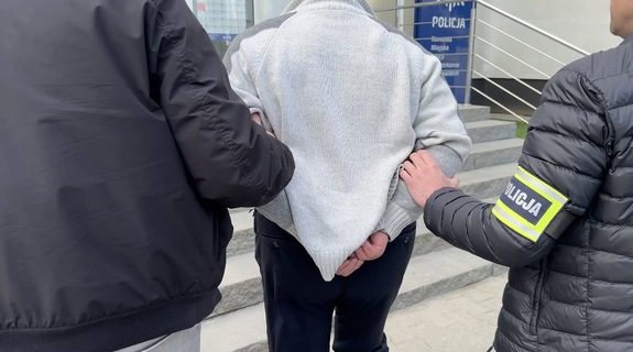 Policjant prowadzi zatrzymanego.