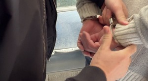 Policjant zakłada zatrzymanemu kajdanki na ręce.