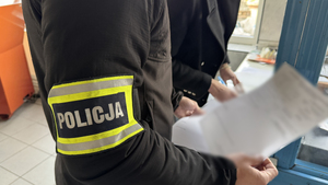 Policjant trzyma w ręku dokumenty.