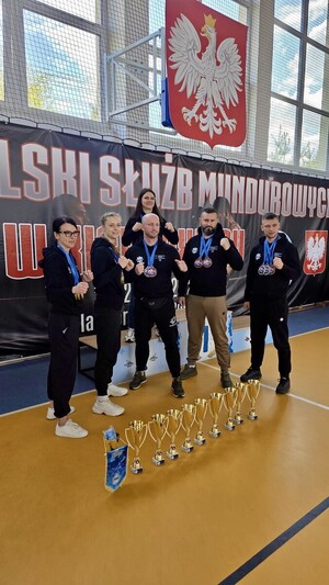 Policjanci stojący przed podium z medalami i pucharami.