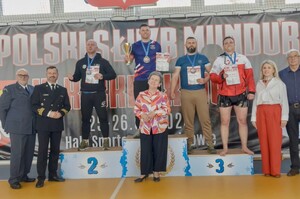 Policjanci stojący na podium z medalami i dyplomami w ręku.