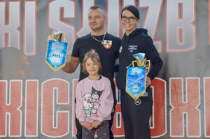 policjantka i policjant na zawodach z pucharami w ręku i dziecko.