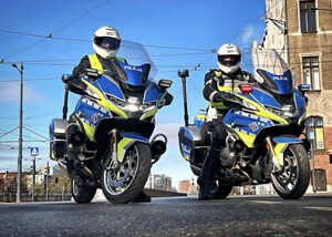 Dwóch umundurowanych policjantów siedzących na oznakowanych motocyklach.
