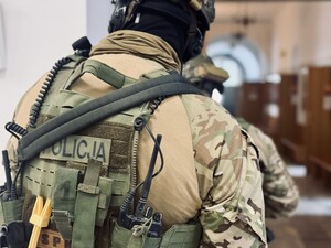 Umundurowany policjant stojący tyłem.