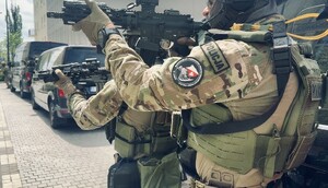Umundurowani policjanci z bronią w ręku przed budynkiem.